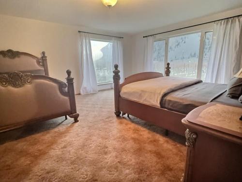 a bedroom with two beds and two windows at Vineyard Home Casa De Herrera in Keremeos