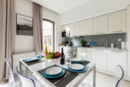 a kitchen with white cabinets and a table with blue dishes at Apartamenty Gdańsk EU - Waterlane in Gdańsk