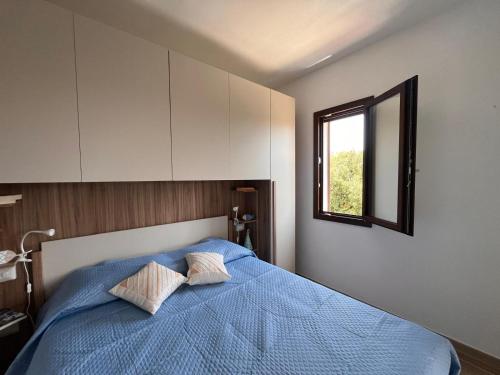1 dormitorio con cama azul y ventana en Porto Columbu, en Porto Columbu - Perdʼe Sali