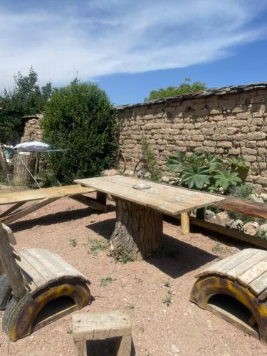 a wooden picnic table and benches in front of a stone wall at Сайма Таш in Bokonbayevo