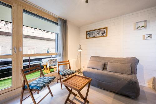 un salon avec un canapé, des chaises et une fenêtre dans l'établissement Studio Skis Aux Pieds, à Peisey-Nancroix