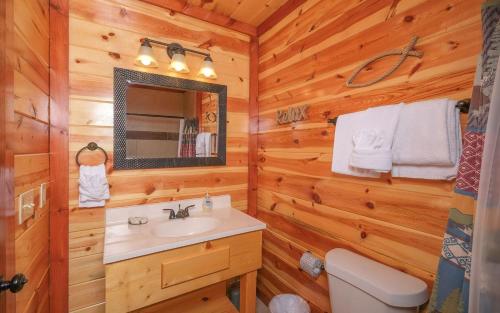 a bathroom with a sink and a mirror in a log cabin at Splash N Mountain Lookout in Pigeon Forge
