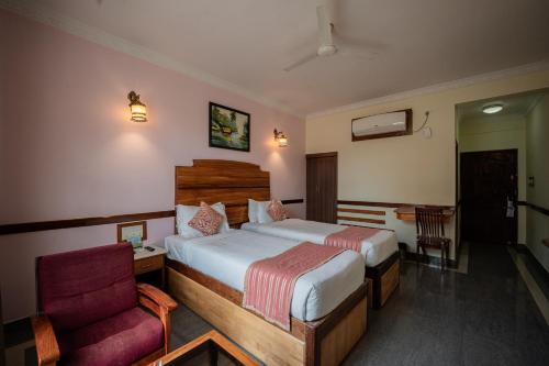 a hotel room with a bed and a chair at Hotel Presidency Kempegowda International Airport Bangalore in Devanahalli-Bangalore