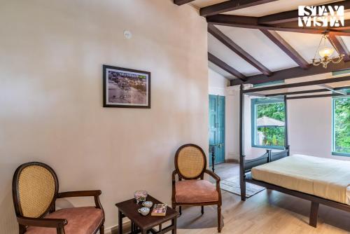 a bedroom with a bed and two chairs at StayVista at The Emily Chalet 7 BR House in Nainital with Bonfire, BBQ in Nainital