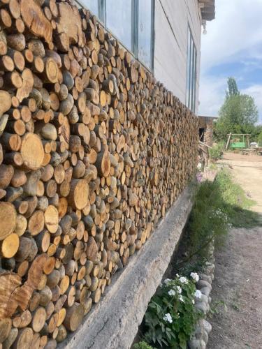 a wall full of logs next to a building at Сайма Таш in Bokonbayevo