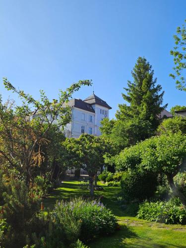 a large white house in the middle of a garden at Hotel Marmułowski in Wejherowo