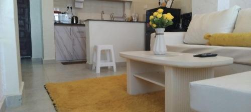 a living room with a white couch and a table with flowers at Yellow Petals Homestays in Nanyuki