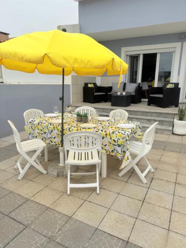 a table and chairs with a yellow umbrella at LS Beach House in A dos Cunhados