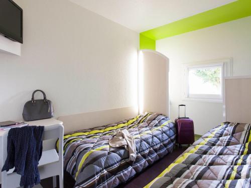 a room with two beds and a tv and a window at hotelF1 Merlebach Saarbrueck in Merlebach