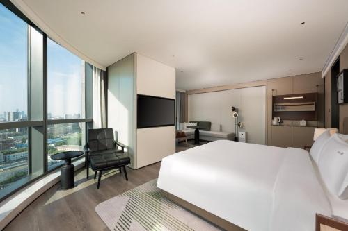 a bedroom with a large white bed and a chair at Holiday Inn Changchun High Tech Zone by IHG in Changchun