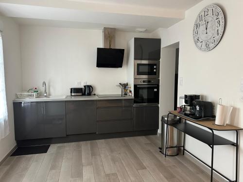 une cuisine avec des armoires noires et une horloge murale dans l'établissement la grande aire, à Saint-Aignan