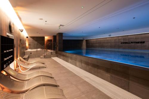a swimming pool in a hotel with benches and a tub at DoubleTree by Hilton Wroclaw in Wrocław