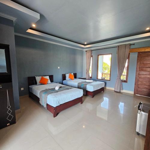 a bedroom with two beds and a flat screen tv at Ridho Malik Hotel in Bumbang