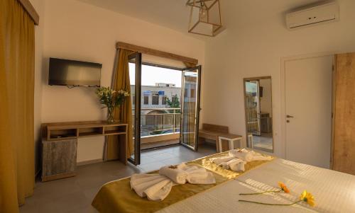 a bedroom with a bed and a tv and a balcony at Castell Hotel in Kissamos