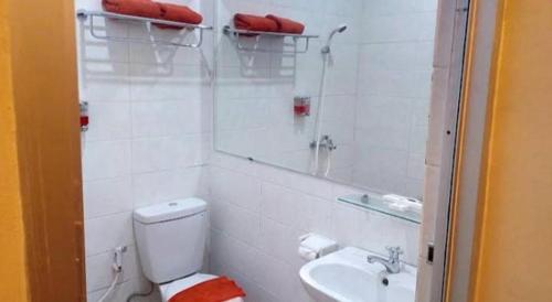 a white bathroom with a toilet and a sink at The Margangsa Hotel in Solo