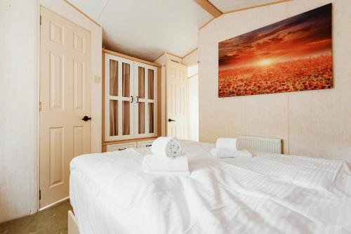 a white bed in a bedroom with a painting on the wall at Villa Hexenholz in Thale