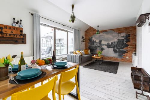 a kitchen and living room with a table and yellow chairs at Apartamenty Gdańsk EU - Waterlane in Gdańsk