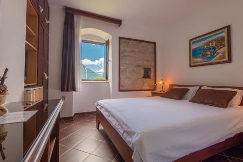 ein Schlafzimmer mit einem großen Bett und einem Fenster in der Unterkunft Apartments Babilon in Kotor