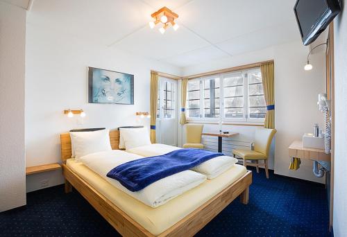 a bedroom with a bed with a blue blanket on it at Hotel Alpina in Mürren
