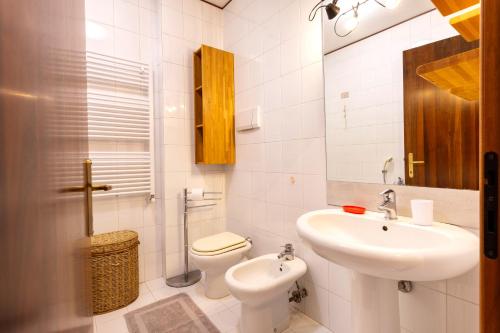a white bathroom with a sink and a toilet at Via Moro - Home 86 in Quarto dʼAltino