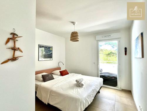 une chambre avec un lit avec des draps blancs et une fenêtre dans l'établissement Le Coba Beach - P3 Cosy, Clim, Parking, Plage à 10 min à pied, à La Grande Motte