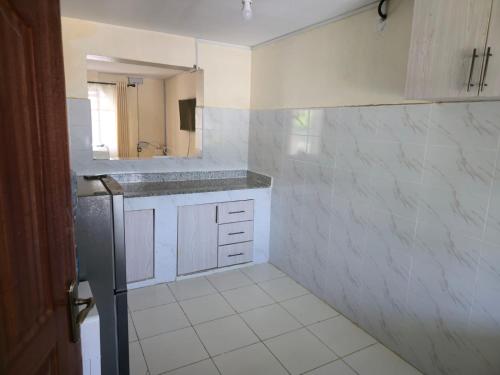a white kitchen with a sink and a mirror at Nyodera Homes Furnished Apartments in Oyugis