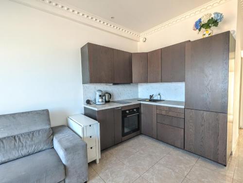 une cuisine avec des armoires marron et un canapé dans une pièce dans l'établissement Appartement SEA-Azur panorama Nice Fabron, à Nice