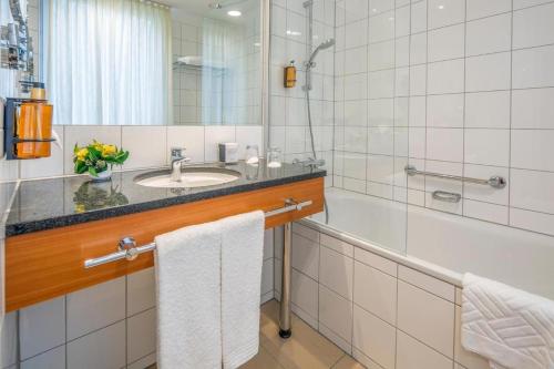 a bathroom with a sink and a shower and towels at Ibercity Wien Schönbrunn in Vienna