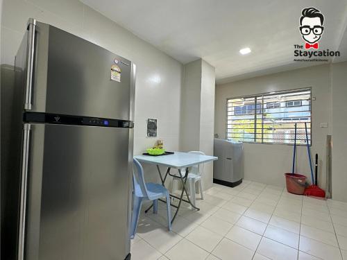 a kitchen with a stainless steel refrigerator and a table at Staycation Homestay 15 Kch City Mall Landed House in Kuching