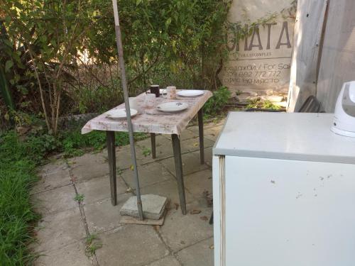 an old table with plates on it in a yard at Бунгало с терасата in Ahtopol