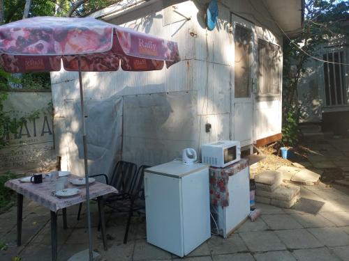 a patio with a table and an umbrella and a refrigerator at Бунгало с терасата in Ahtopol