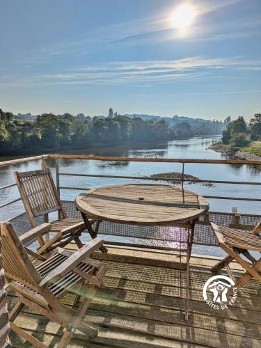 a table and chairs on a deck with a view of a river at Moulin de la Rongère in Saint-Sulpice