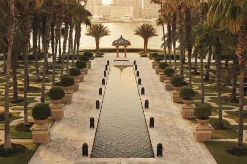 迪拜One&Only Royal Mirage Resort Dubai的公园里一条有树木和水的步道