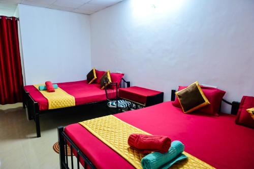 a room with three beds with red and yellow at Kumbles Misty Mount in Attigundi