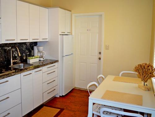 a kitchen with white cabinets and a table and a refrigerator at Ocean Drive Villas in Hollywood