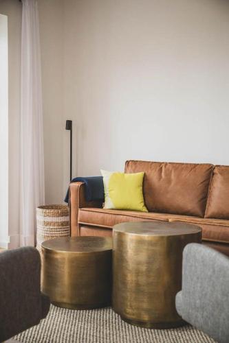 a living room with a couch and two gold tables at Appartements Brigg & Schoner in Neuharlingersiel
