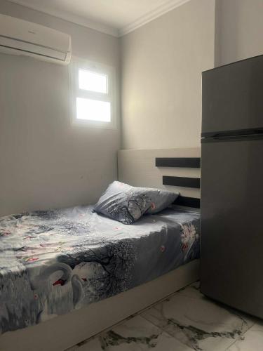 a small bedroom with a bed and a refrigerator at Porto marina Panoramica sea view in front marina 2 in El Alamein