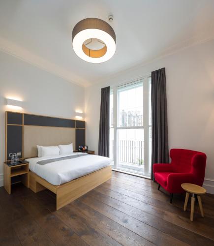 a bedroom with a bed and a red chair at The Z Hotel Gloucester Place in London