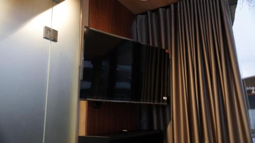 a flat screen tv on a wall next to a curtain at Peegelmaja in Otepää