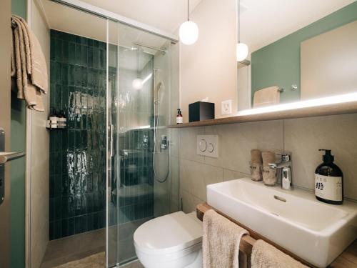a bathroom with a shower and a toilet and a sink at KURVE Apartments & Lounge in Adelboden
