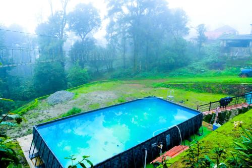 a swimming pool in a grassy field next to at Kumbles Misty Mount in Attigundi