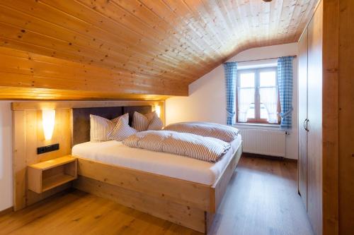 une chambre avec un grand lit avec un plafond en bois dans l'établissement Aschenauer Hof, à Ruhpolding