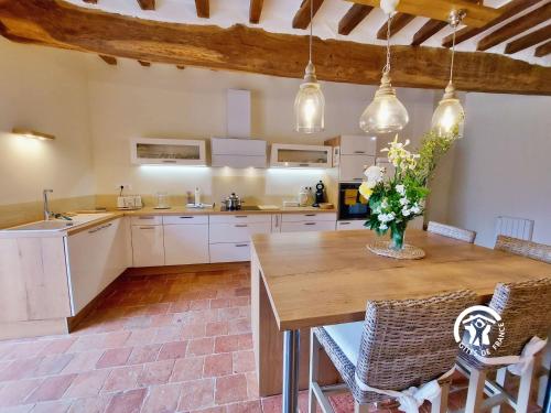 a large kitchen with a wooden table and chairs at Le plessis aux oiseaux, jusqu'à 14 personnes in Saint-Fort