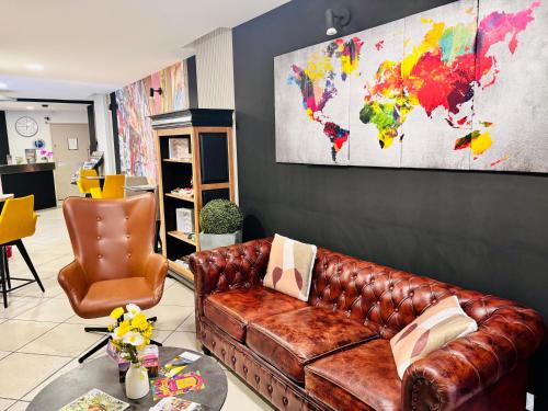 a living room with a leather couch and a world map on the wall at Hotel Le Gambetta in Bergerac