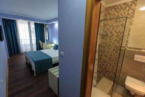 a hotel room with a bed and a bathroom with a shower at Sirena Marta in Sutomore