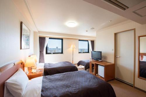 a hotel room with two beds and a television at Albert Hotel in Akita