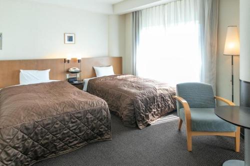 a hotel room with two beds and a table and a chair at Ou Hotel in Yonago