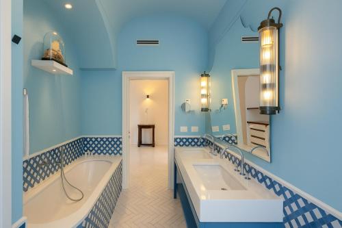a blue bathroom with two sinks and a tub at Grand Hotel Europa Palace Sorrento in Sorrento