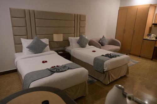 a hotel room with two beds and a chair at Best Western Plus Mahboula in Kuwait