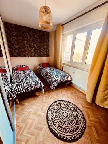 une chambre avec deux lits et un tapis dans l'établissement Colmar'INN Bel Hypercentre Colmar Ascenseur-Parking privé en sous sol -Free Wifi, à Colmar